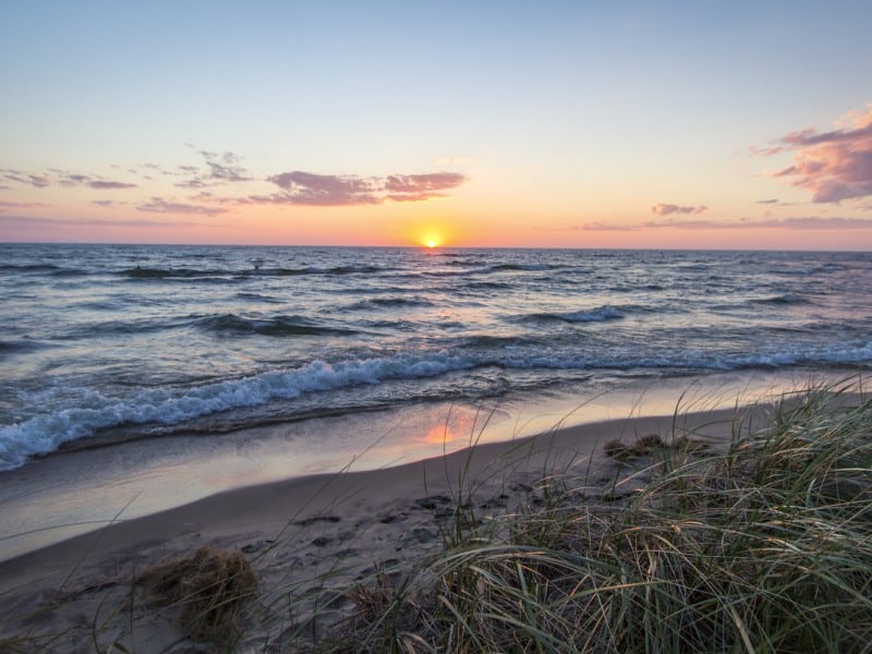 Sunset over a grassy Great Lakes beach.