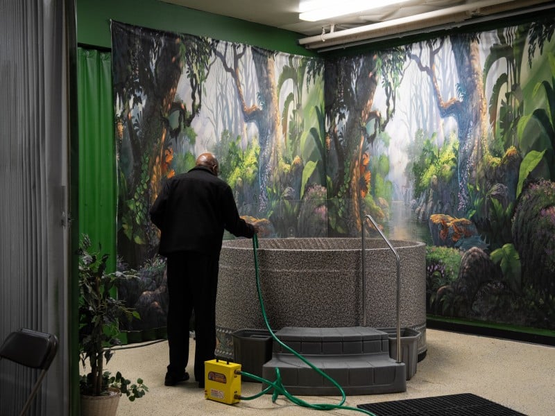 A person uses a hose to fill up a tub of water