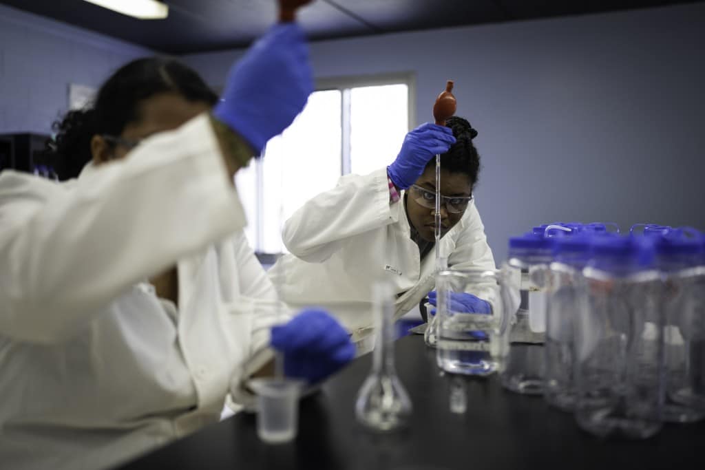 Two people in white coats work in a lab 