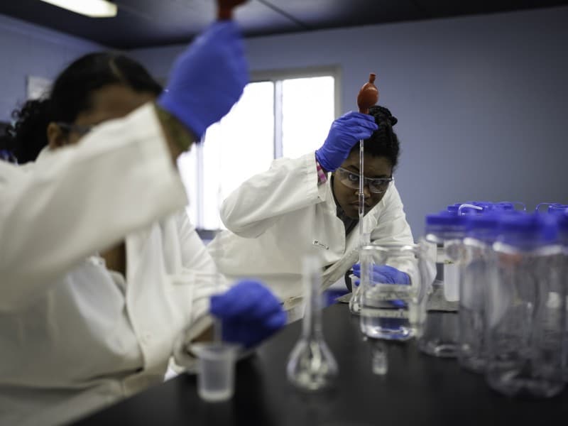 Two people in white coats work in a lab