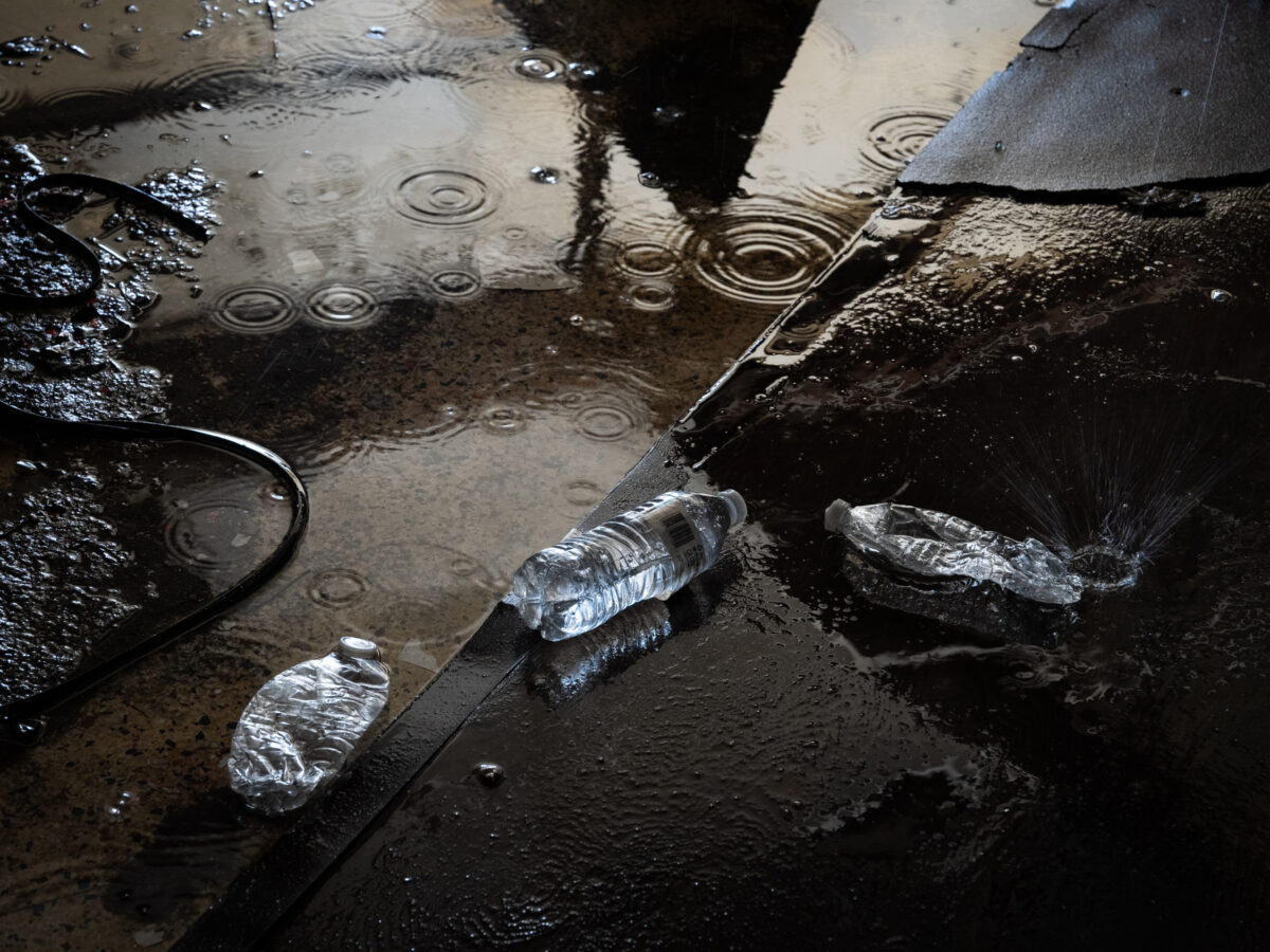 Water bottles discarded on the floor in a puddle.