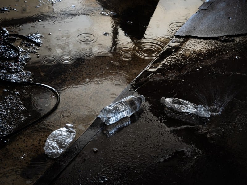 Water bottles discarded on the floor in a puddle.