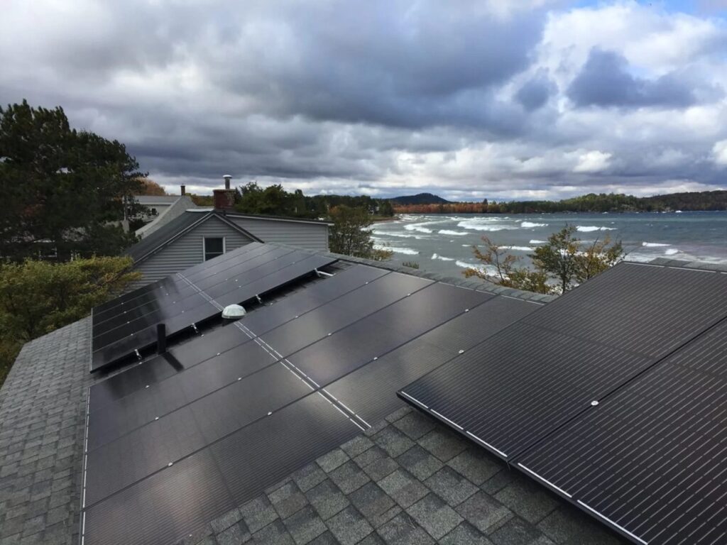 A close up of solar panels on a roof against a cloudy sky.