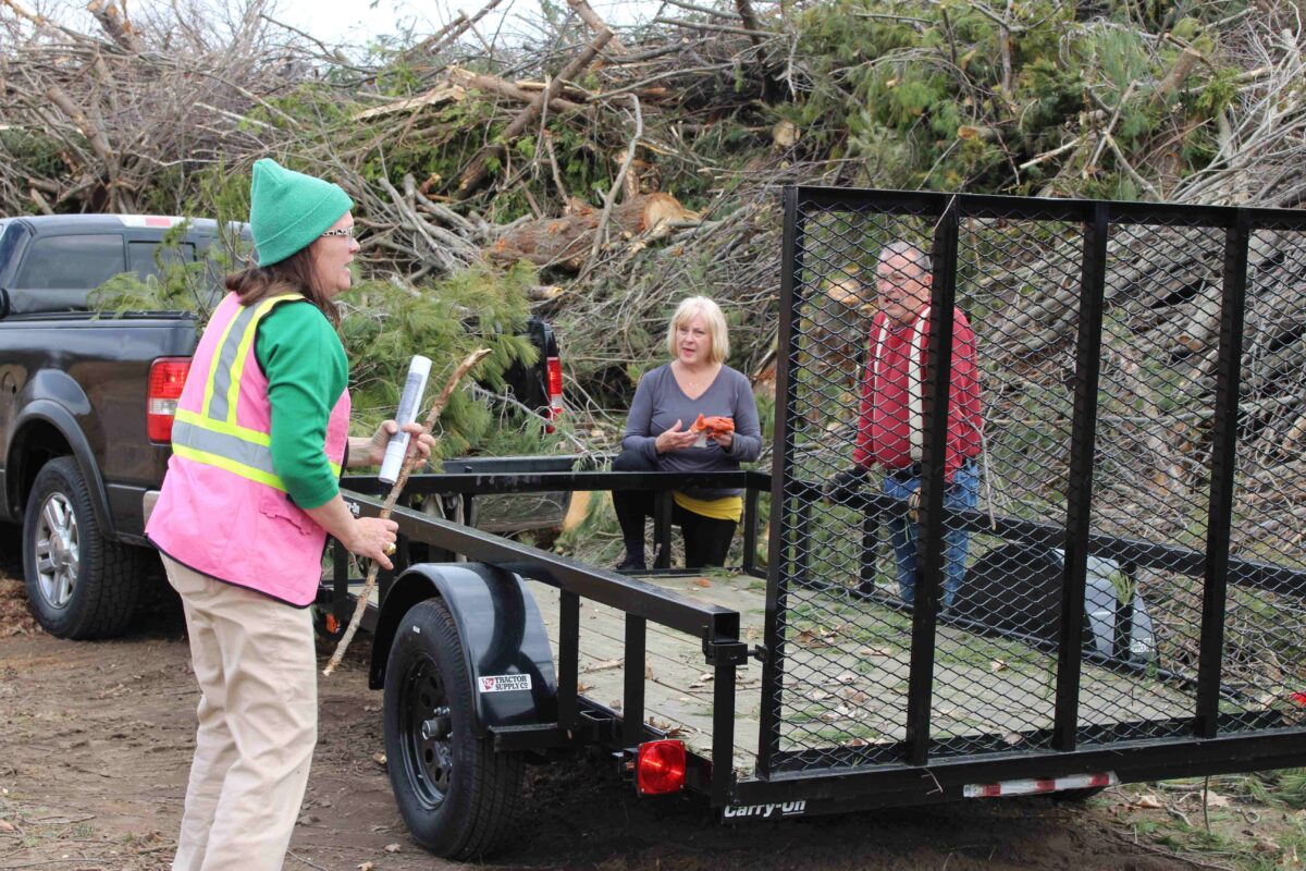 Three people talk at an Emmet County, Michigan debris dropoff site