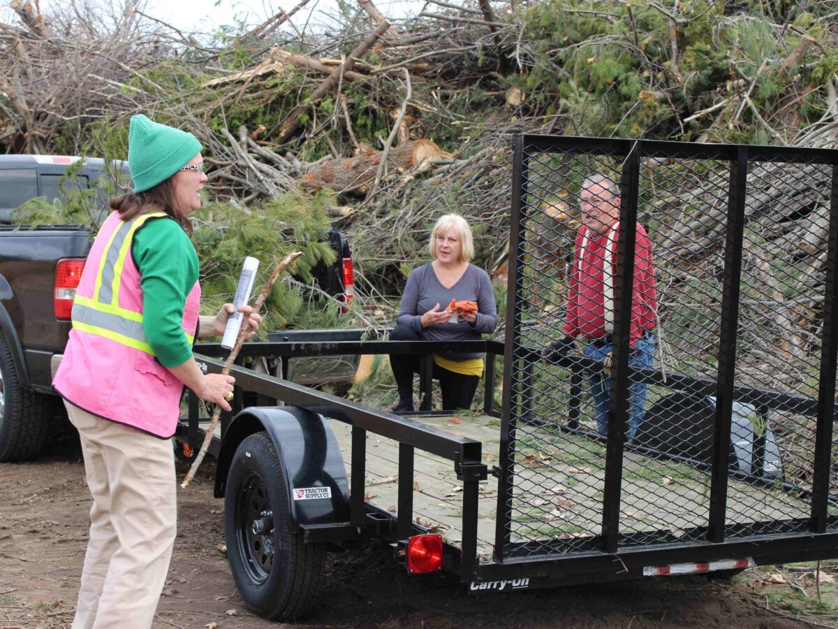 Three people talk at an Emmet County, Michigan debris dropoff site