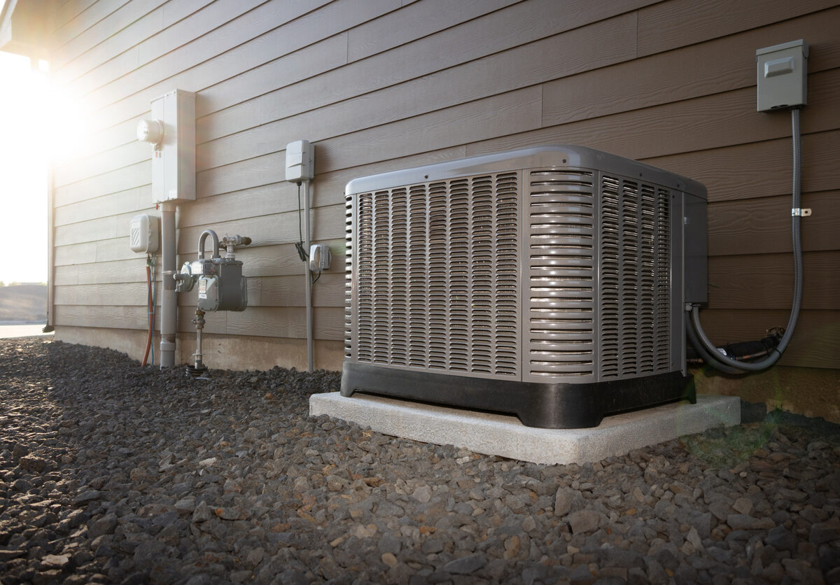 Modern HVAC air conditioner unit on concrete slab outside of duplex house.