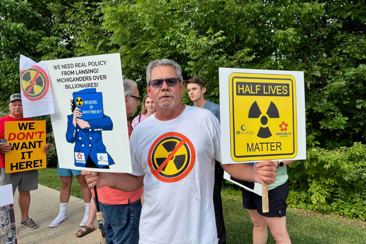 Van Buren Township resident Chris Donley holds signs outside meeting on Republic Services facility, including "Half Lives Matter" sign.