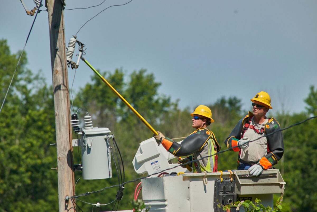 Two Consumers Energy line workers doing repair work from a bucket lift