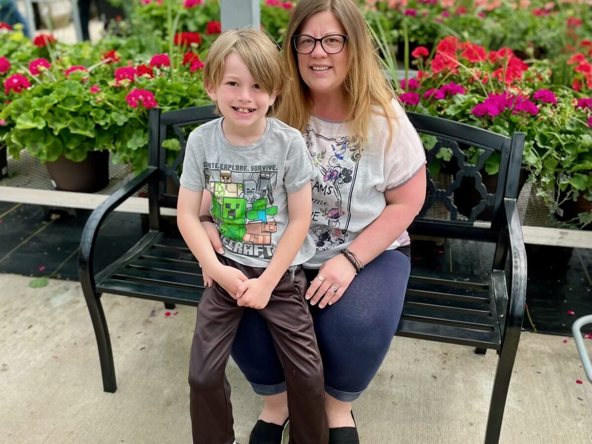 Wyandotte resident Erin Craig sits on a bench with her son, Ethan, in front of flowers.