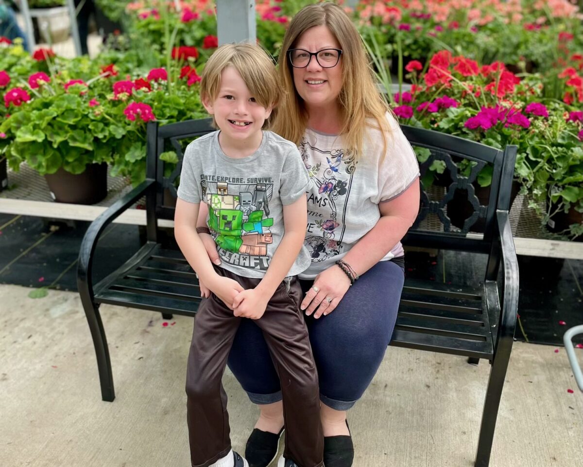 Wyandotte resident Erin Craig sits on a bench with her son, Ethan, in front of flowers.