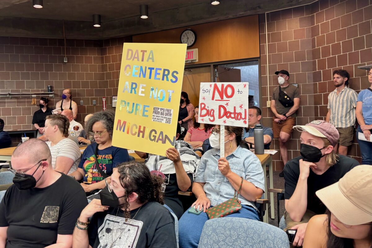 Audience members hold signs in opposition to a University of Michigan data center project at the June 17 Ypsilanti Township board meeting.