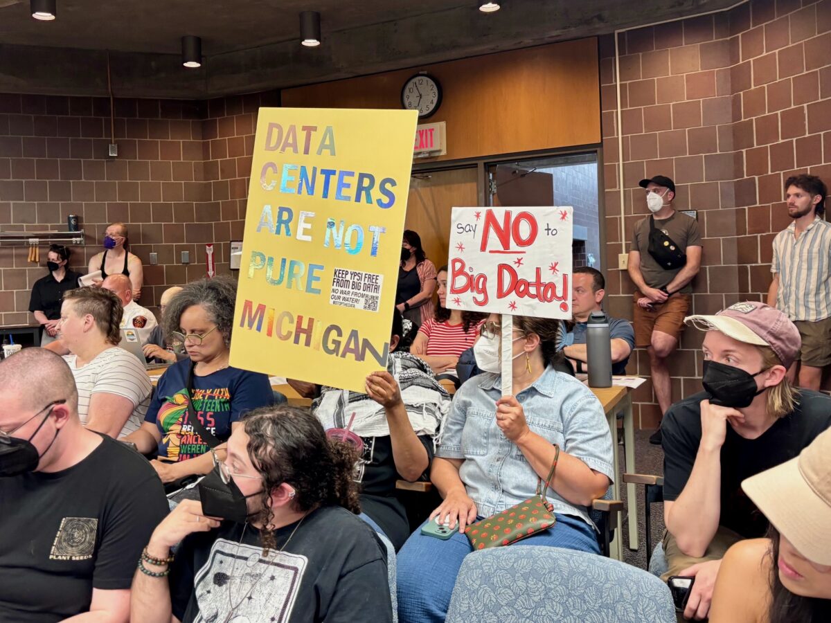 Audience members hold signs in opposition to a University of Michigan data center project at the June 17 Ypsilanti Township board meeting.