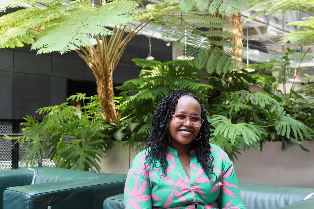 Mary-Jacqueline Muli, founder of The Climate Justice Nurse, sits in front of indoor trees.
