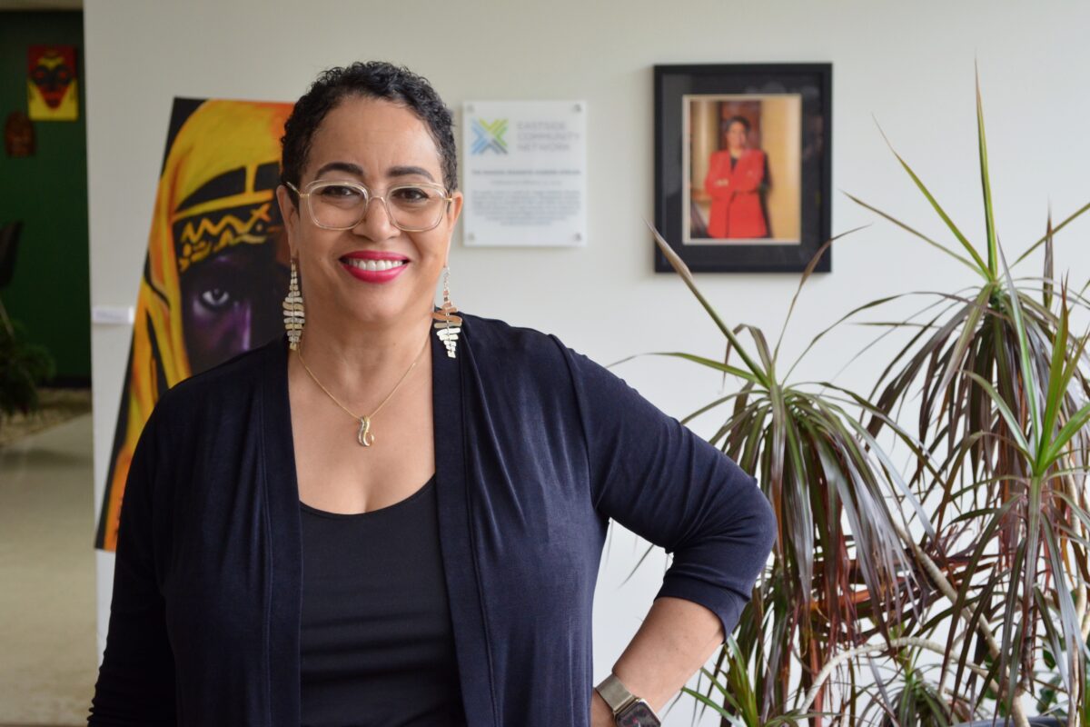 Donna Givens Davidson of Eastside Community Network stands in an office decorated with an indoor plant and art, with a hand on her hip.