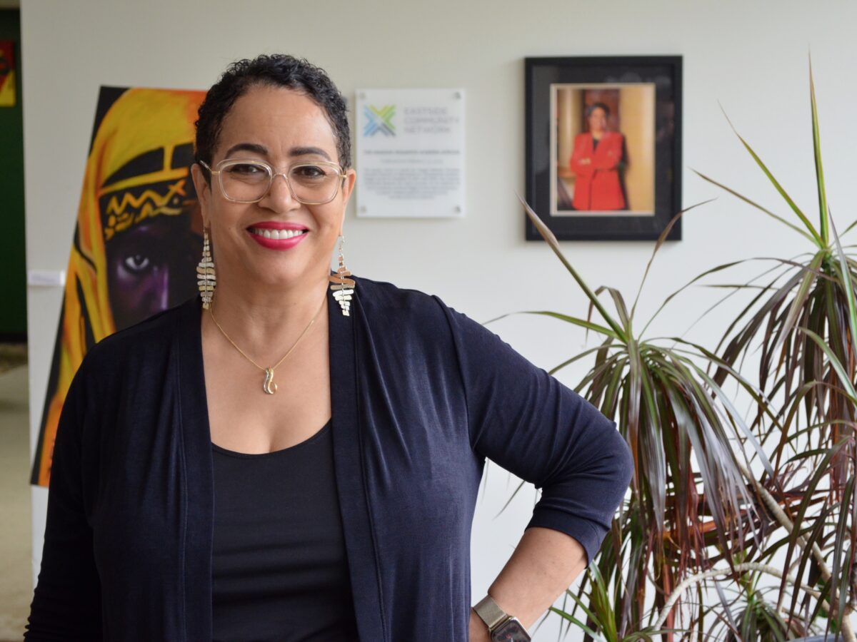 Donna Givens Davidson of Eastside Community Network stands in an office decorated with an indoor plant and art, with a hand on her hip.