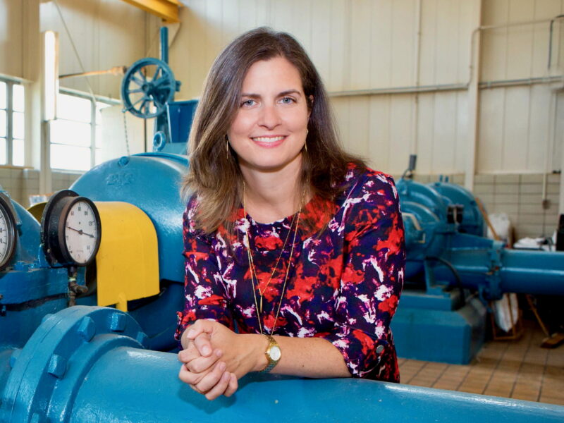 Drinking water expert Elin Betanzo leans on a blue drinking water pipe