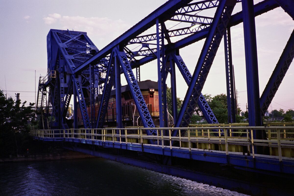 A train crosses a bridge to Zug Island that's painted blue and yellow.