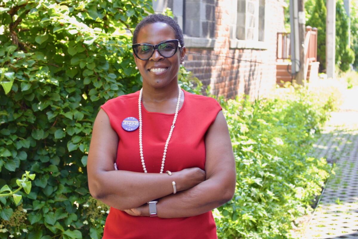 Detroit mayoral candidate Saunteel Jenkins, who is wearing a red shirt, stands with arms crossed.