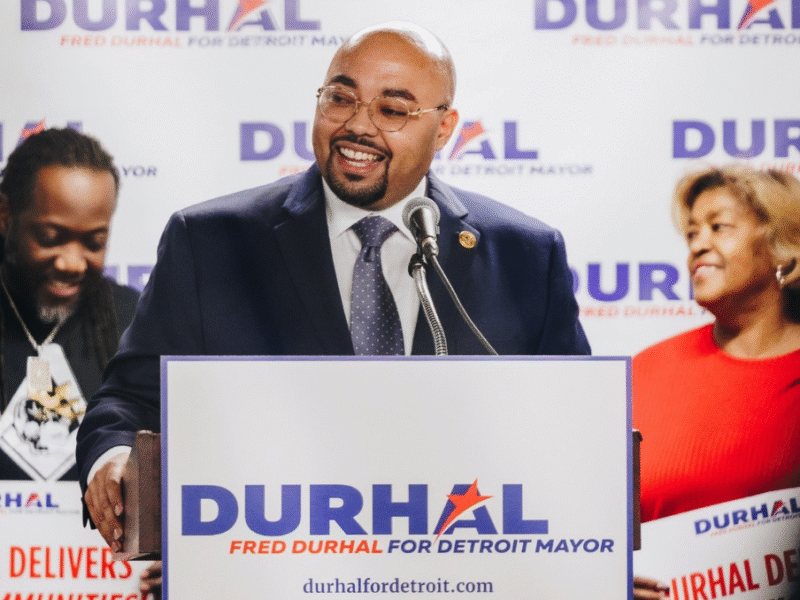 Detroit City Councilmember Fred Durhal III speaks at a podium adorned with campaign signage.