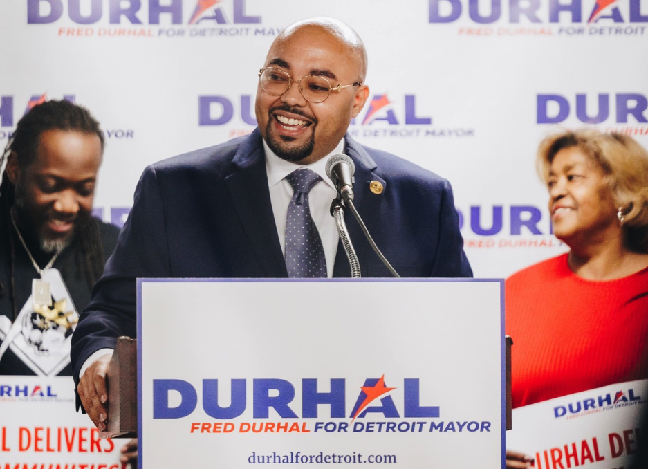 Detroit City Councilmember Fred Durhal III speaks at a podium adorned with campaign signage.