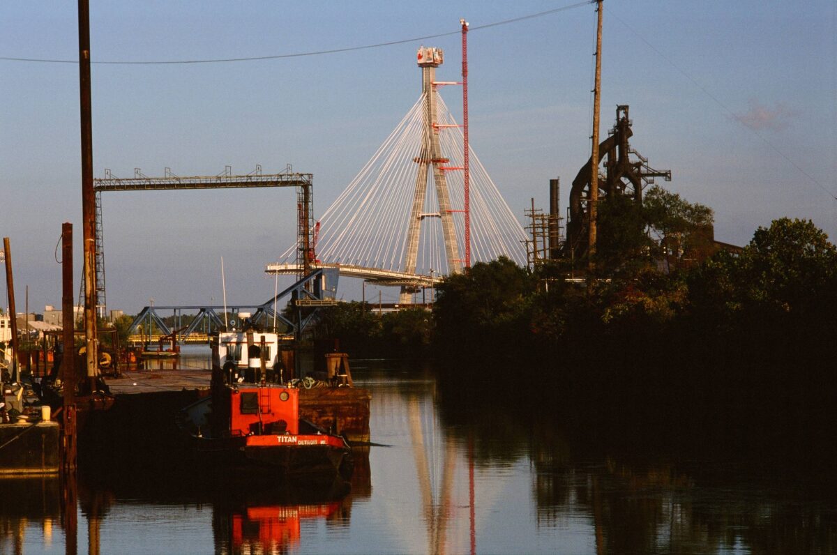 A red tugboat in the River Rouge Old Channel, with Zug Island visible to the right.