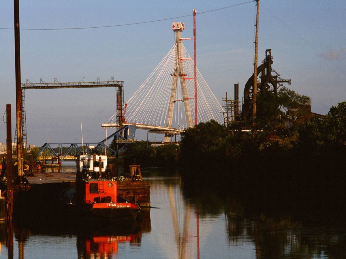 A red tugboat in the River Rouge Old Channel, with Zug Island visible to the right.