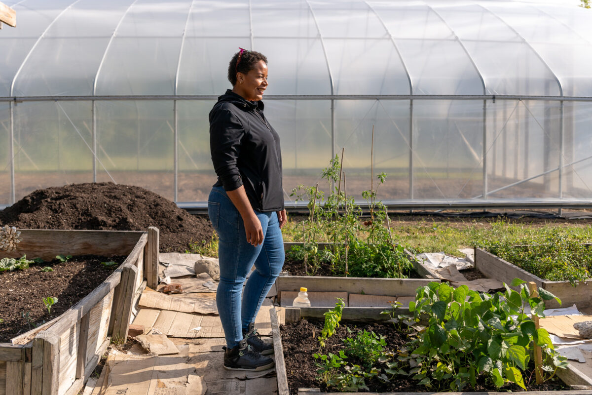 Lynelle Herndon stands in front of a hoop house on her urban farm in Detroit.