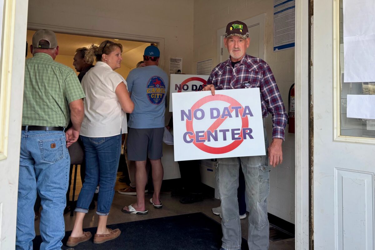 Saline Township resident Fred Gall holds a "no data center" sign outside a board meeting.