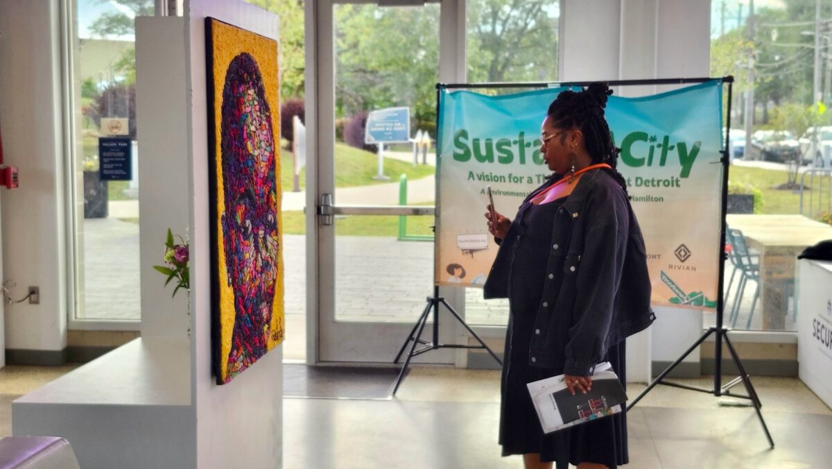 A woman admires a crochet yarn on canvas piece at the Sustain-A-City art exhibition.