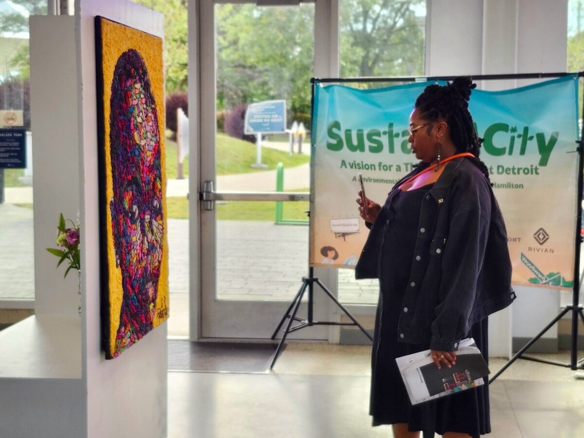 A woman admires a crochet yarn on canvas piece at the Sustain-A-City art exhibition.
