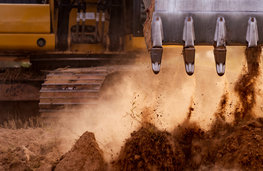 A close up of a backhoe moving dirt