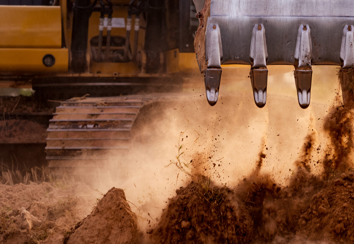 A close up of a backhoe moving dirt
