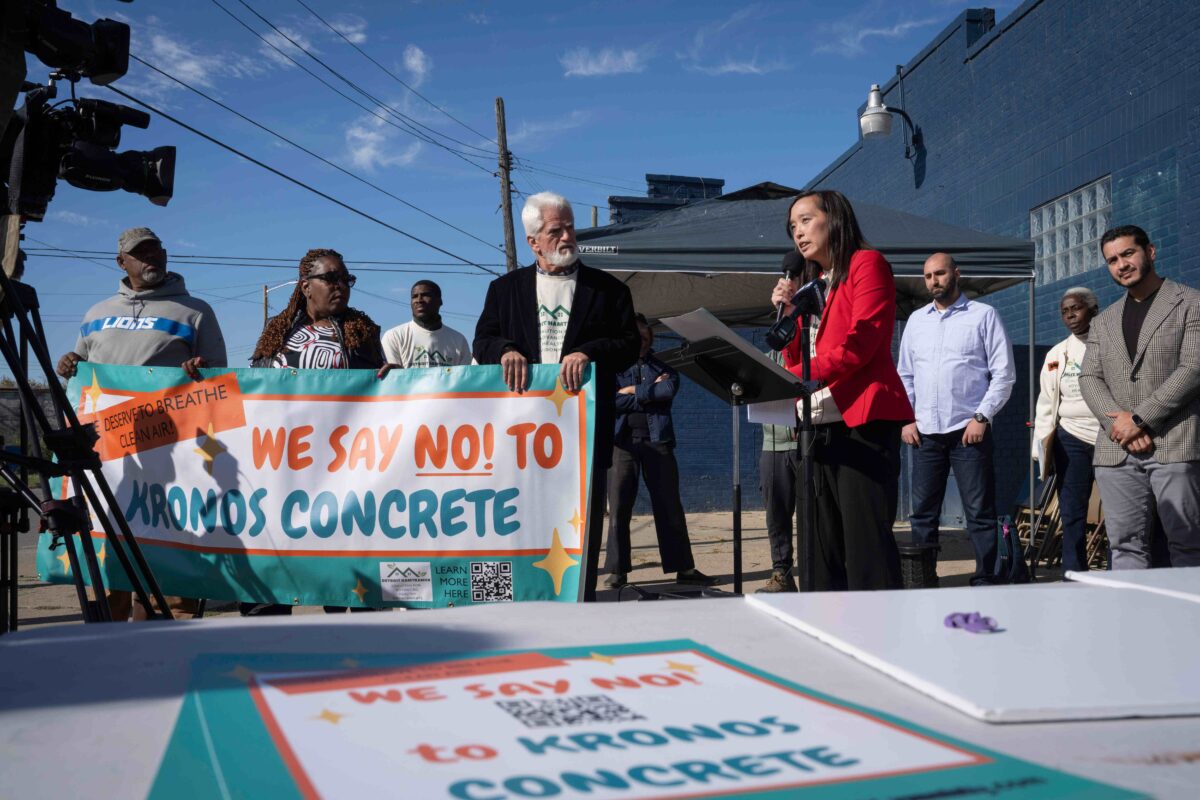 Michigan State Senator Stephanie Chang speaks during a press conference held by the Detroit Hamtramck Coalition for Advancing Healthy Environments demanding the immediate shut down of Kronos concrete facility. Protesters to her left hold a sign that says "We say no! to Kronos Concrete."