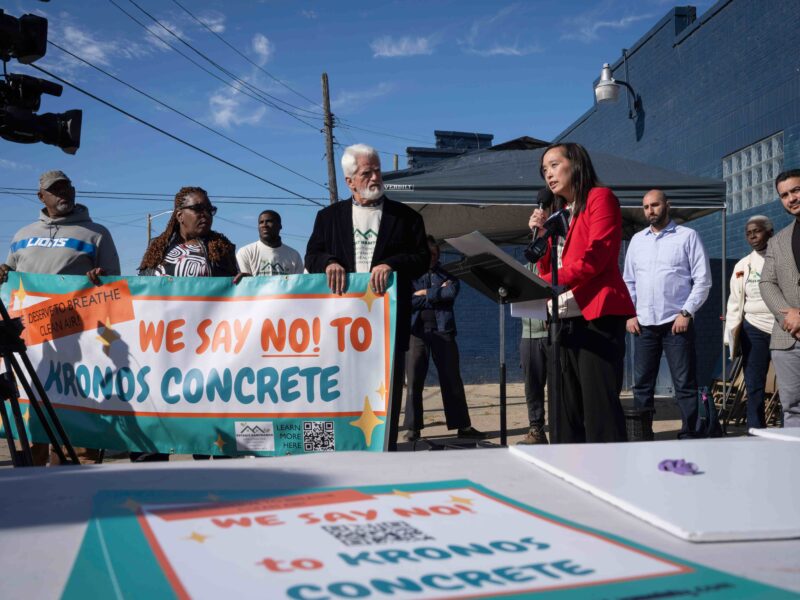 Michigan State Senator Stephanie Chang speaks during a press conference held by the Detroit Hamtramck Coalition for Advancing Healthy Environments demanding the immediate shut down of Kronos concrete facility. Protesters to her left hold a sign that says "We say no! to Kronos Concrete."