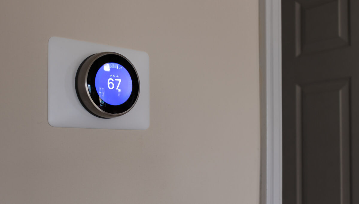 A digital thermostat set to 67 degrees mounted on a wall.