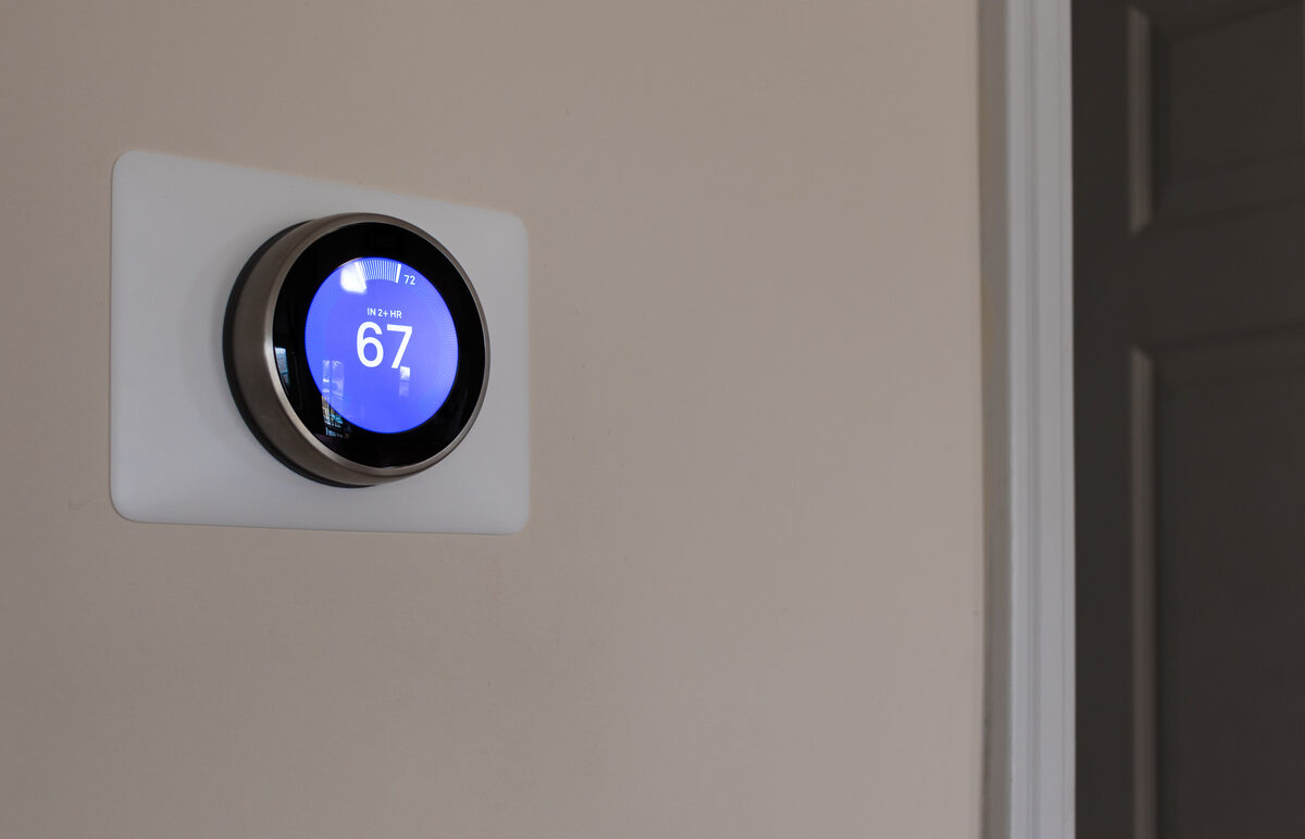 A digital thermostat set to 67 degrees mounted on a wall.