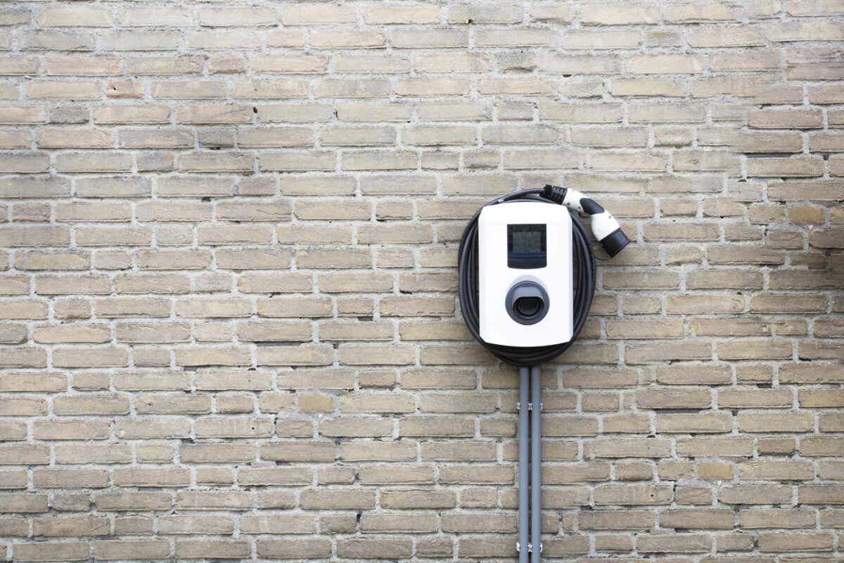 Charging station for electric car on brick wall.