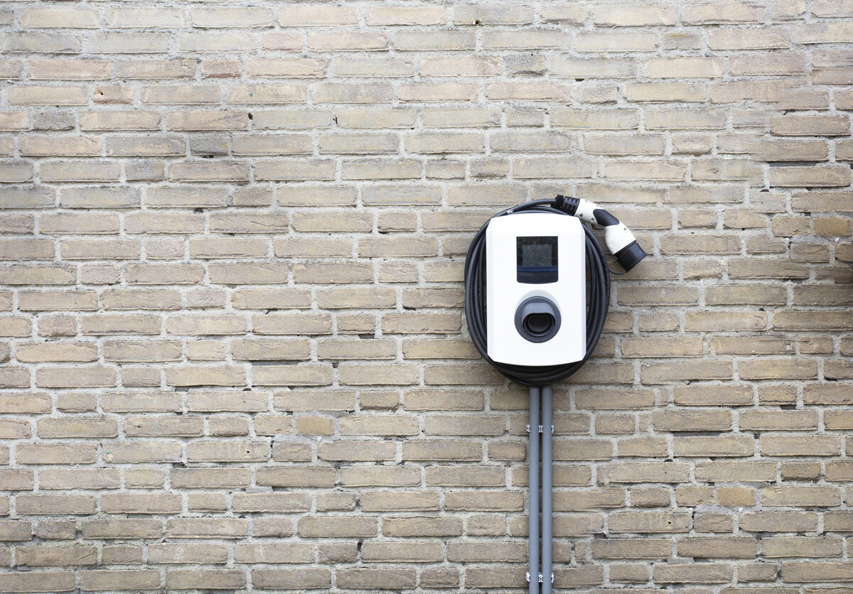 Charging station for electric car on brick wall.
