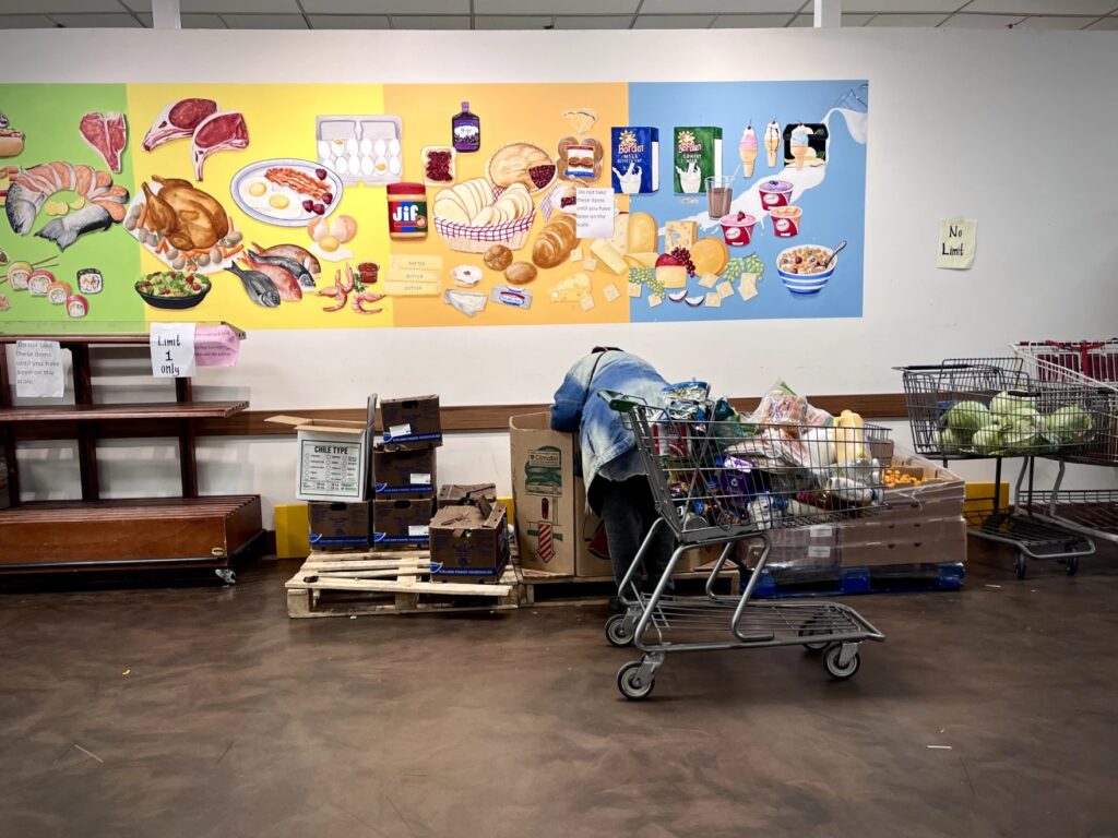 A woman selects a watermelon from the Capuchin Soup Kitchen food pantry.