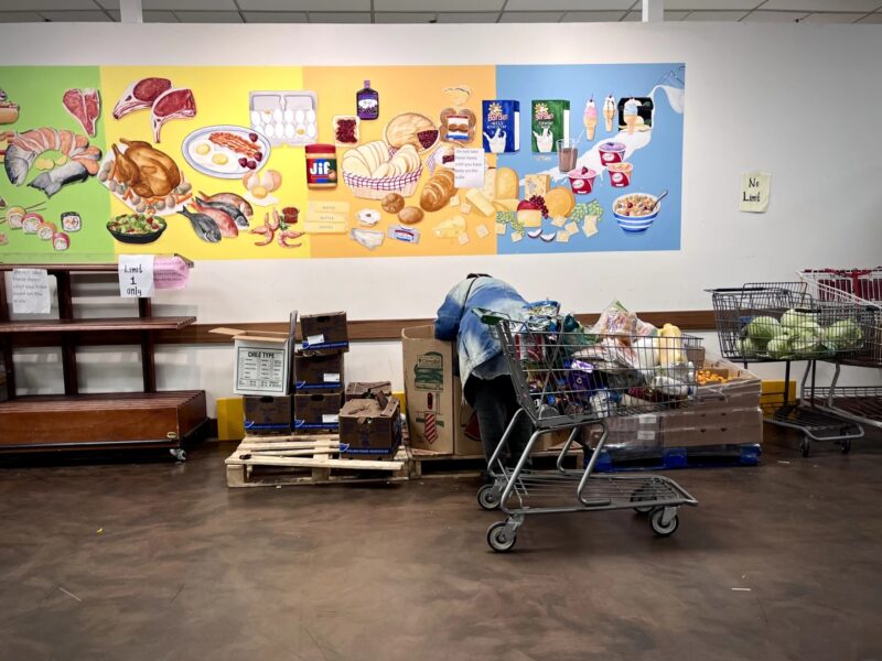 A woman selects a watermelon from the Capuchin Soup Kitchen food pantry.