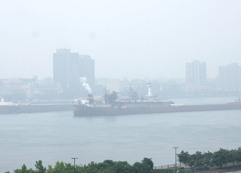 Freighters pass along the Detroit River with Windsor, Ontario in the background as smoke fills the sky reducing visibility Wednesday, June 28, 2023, as seen from Detroit.