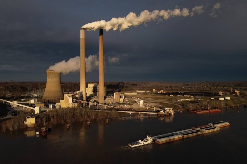 A barge on the Ohio River moves past the Mountaineer Power Plant, a coal-fired power plant near New Haven, W.Va.