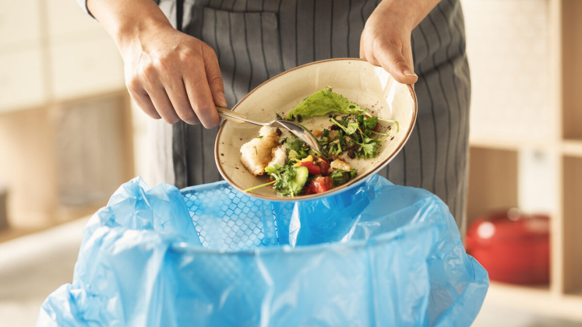 Woman scraping food waste into kitchen bin