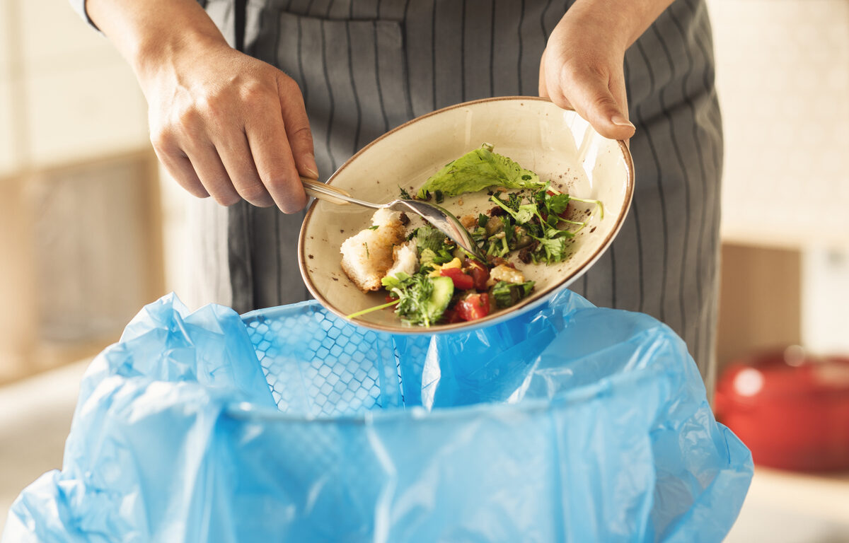 Woman scraping food waste into kitchen bin