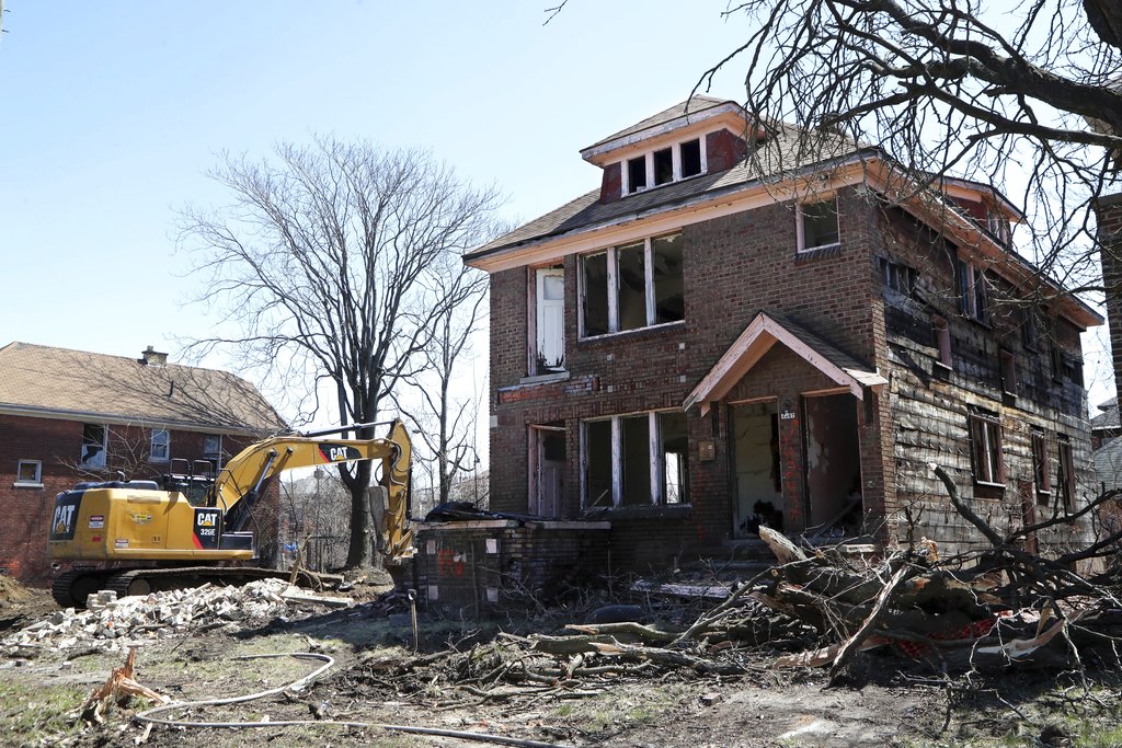 An excavator sits at the site of a house demolition in Detroit.