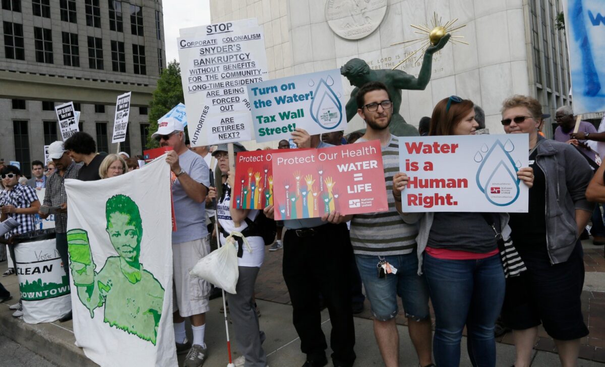 People stand outside Detroit City Hall, protesting thousands of residential water-service shutoffs by Detroit's water department, during a rally in Detroit, Thursday, July 24, 2014.