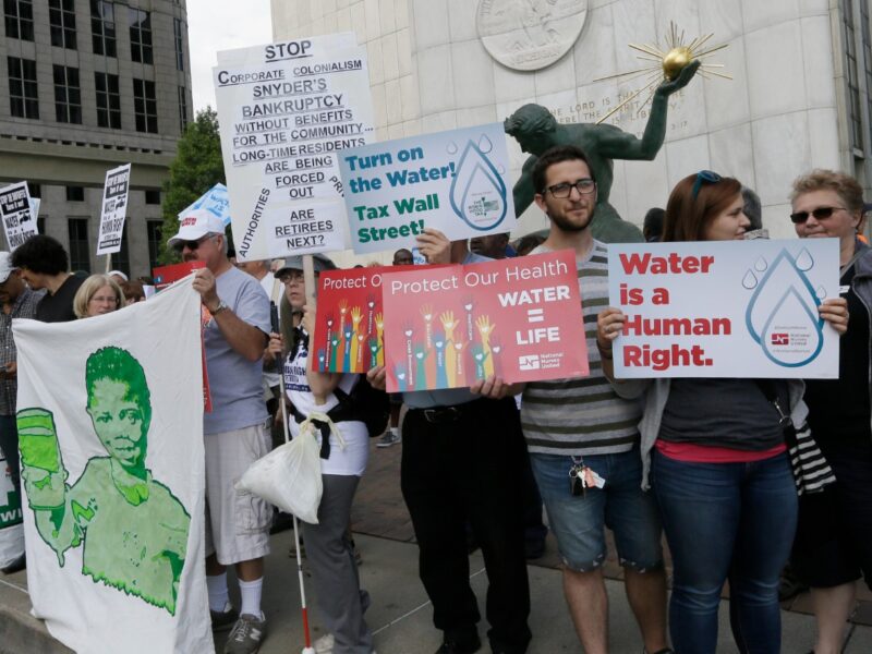 People stand outside Detroit City Hall, protesting thousands of residential water-service shutoffs by Detroit's water department, during a rally in Detroit, Thursday, July 24, 2014.