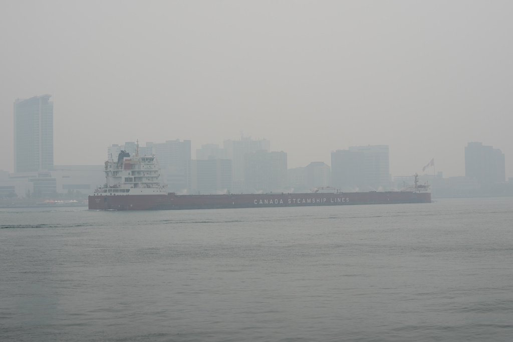 The CSL Welland bulk carrier travels past Windsor, Ontario on the Detroit River during poor air quality due to smoke from Canadian wildfires.