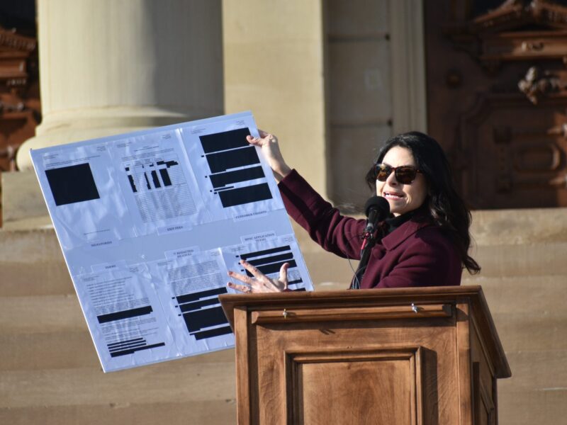 Michigan Attorney General Dana Nessel holds up a sign showcasing redactions in a DTE Energy contract to supply energy to a data center planned in Saline Township